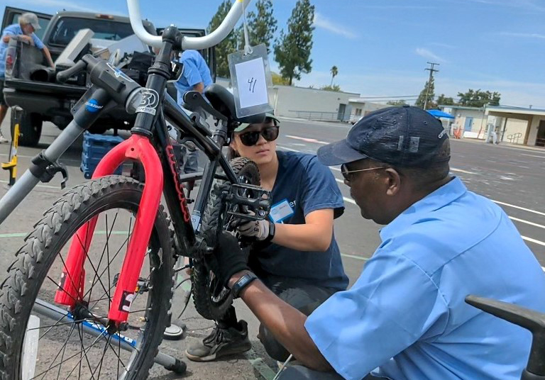 Bev-Ken-repairing-bike crop A man and a woman work on a bicycle outside.