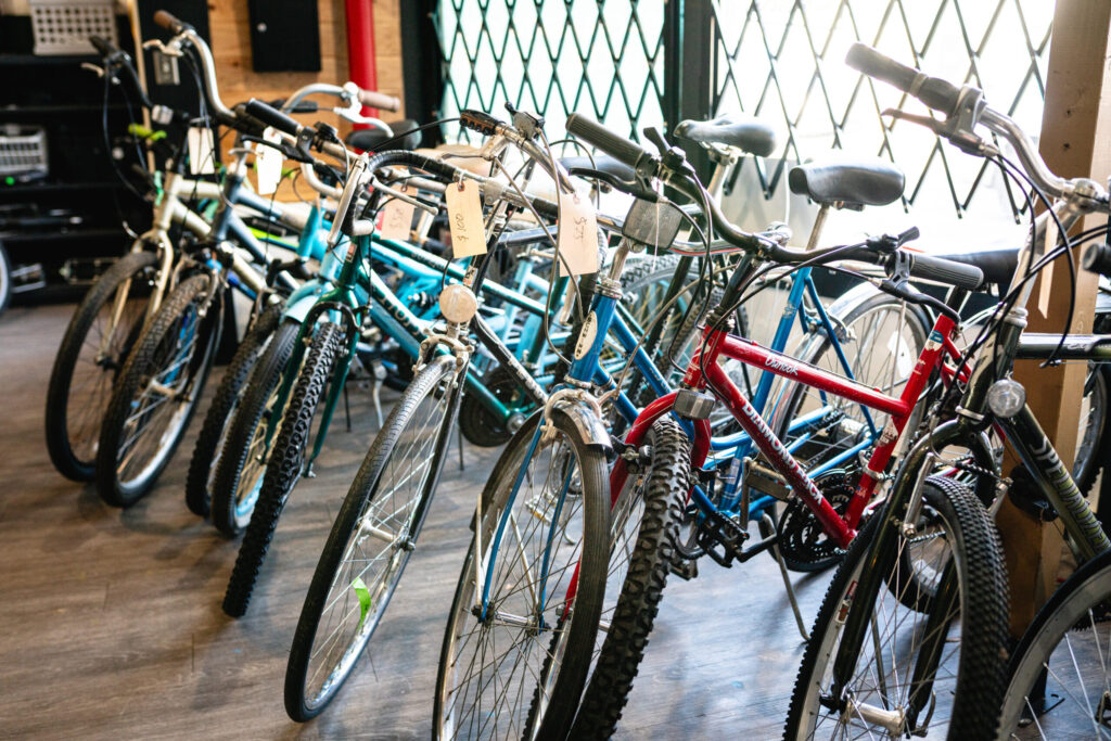 Community_Bike_Shop-26 Row of bikes next to a window - mostly blue or red.
