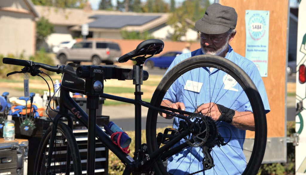 DSC_2733 A man fixes a wheel on a bike that's up on a stand.