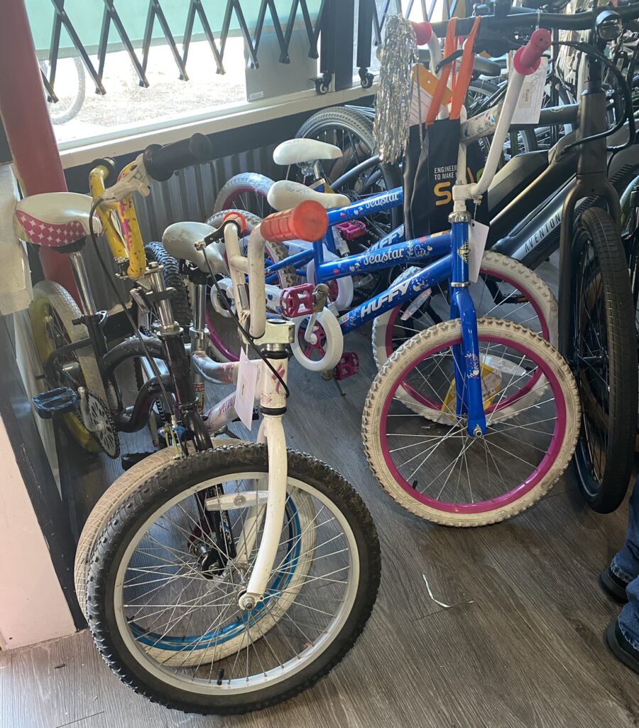 A group of kid's bikes by the shop window.